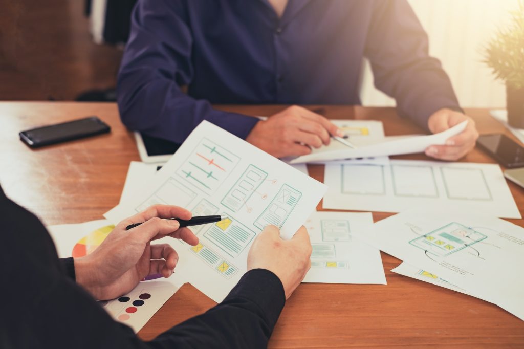 designer creativity drawing a website outline and website ux app development on mobile phone.